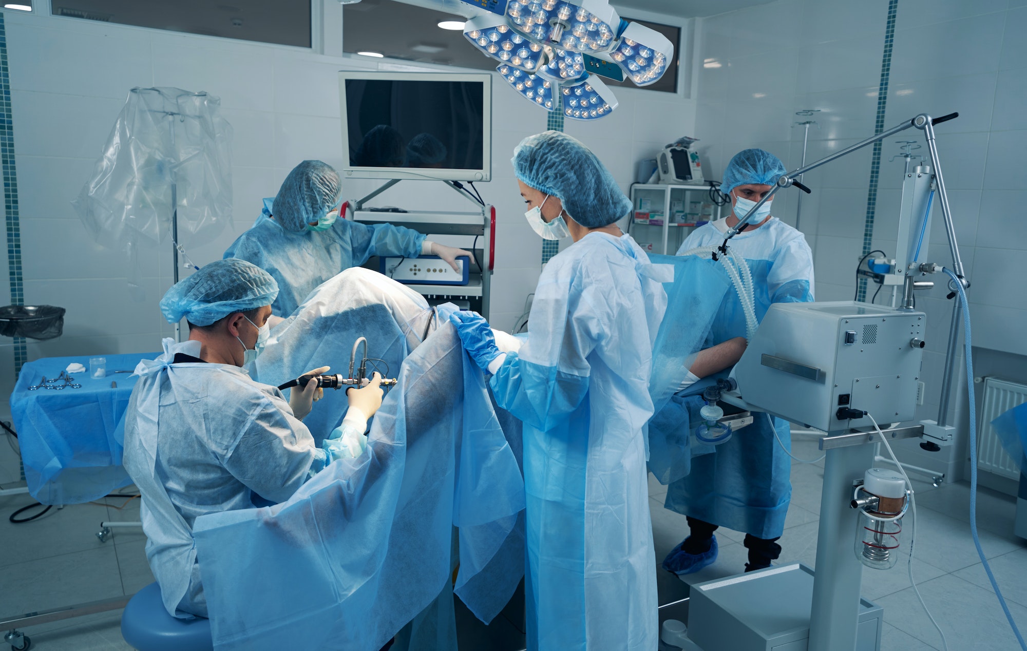 Four surgery specialist in operating theater treating patient